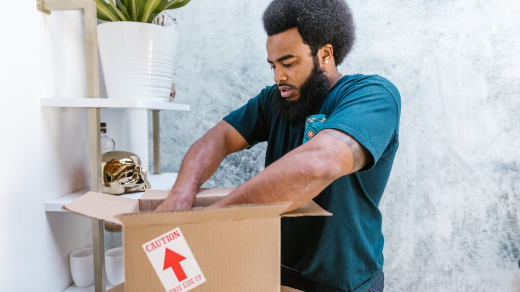 Professional mover carefully packing a fragile item into a box inside a stylish apartment