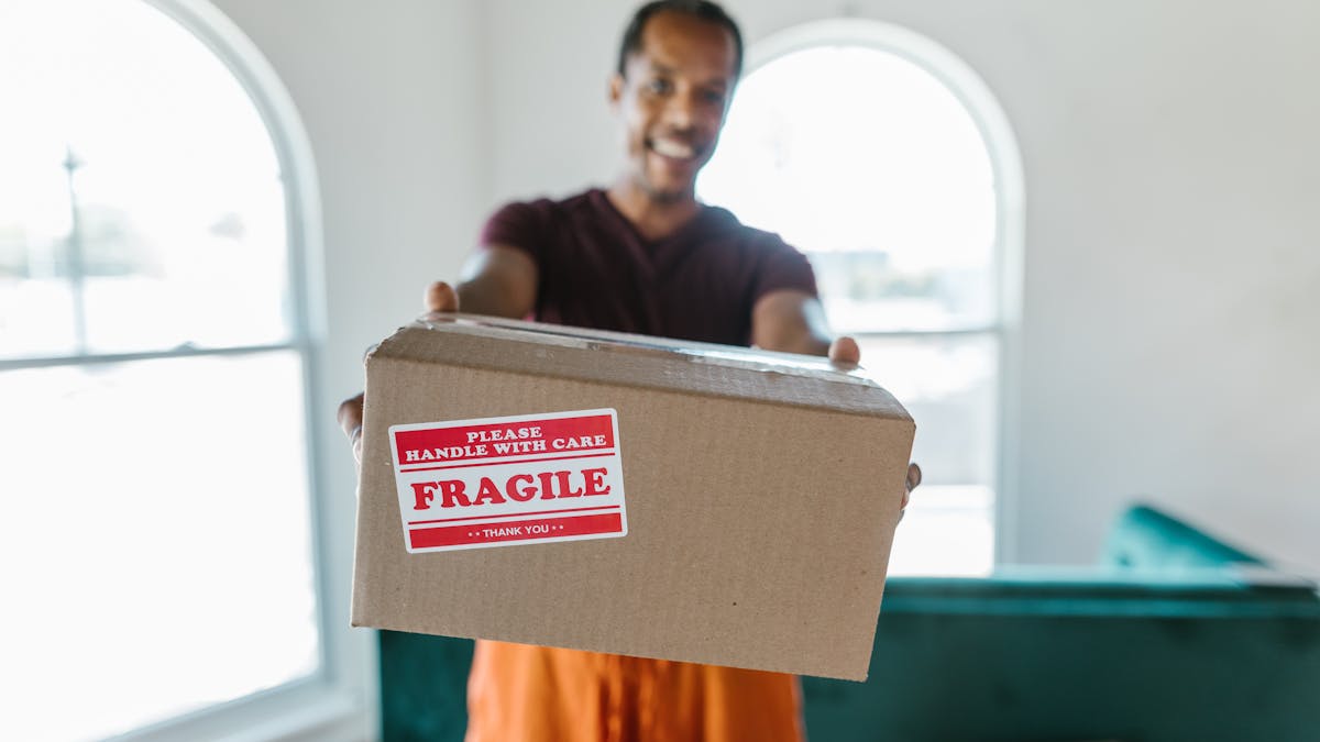 A man holding out a cardboard shipping box.
