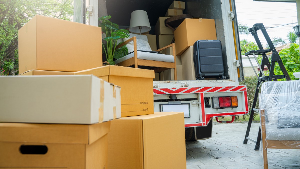 Cardboard boxes and furniture loaded into the back of an open moving truck
