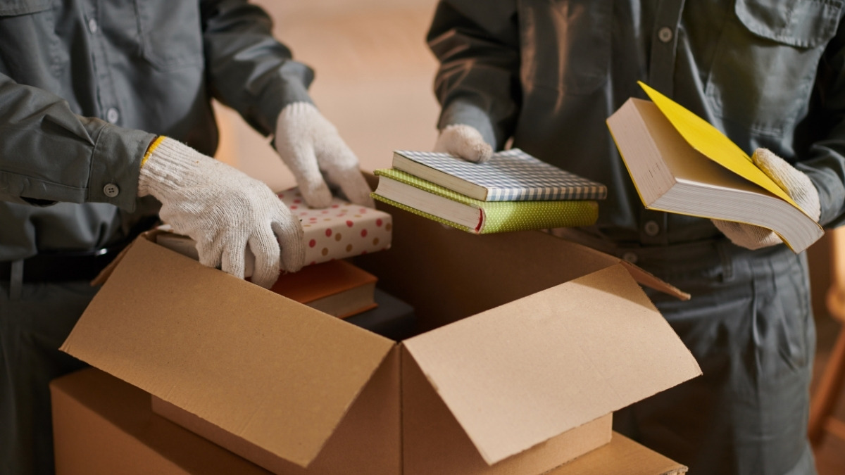 Two workers wearing gloves packing notebooks