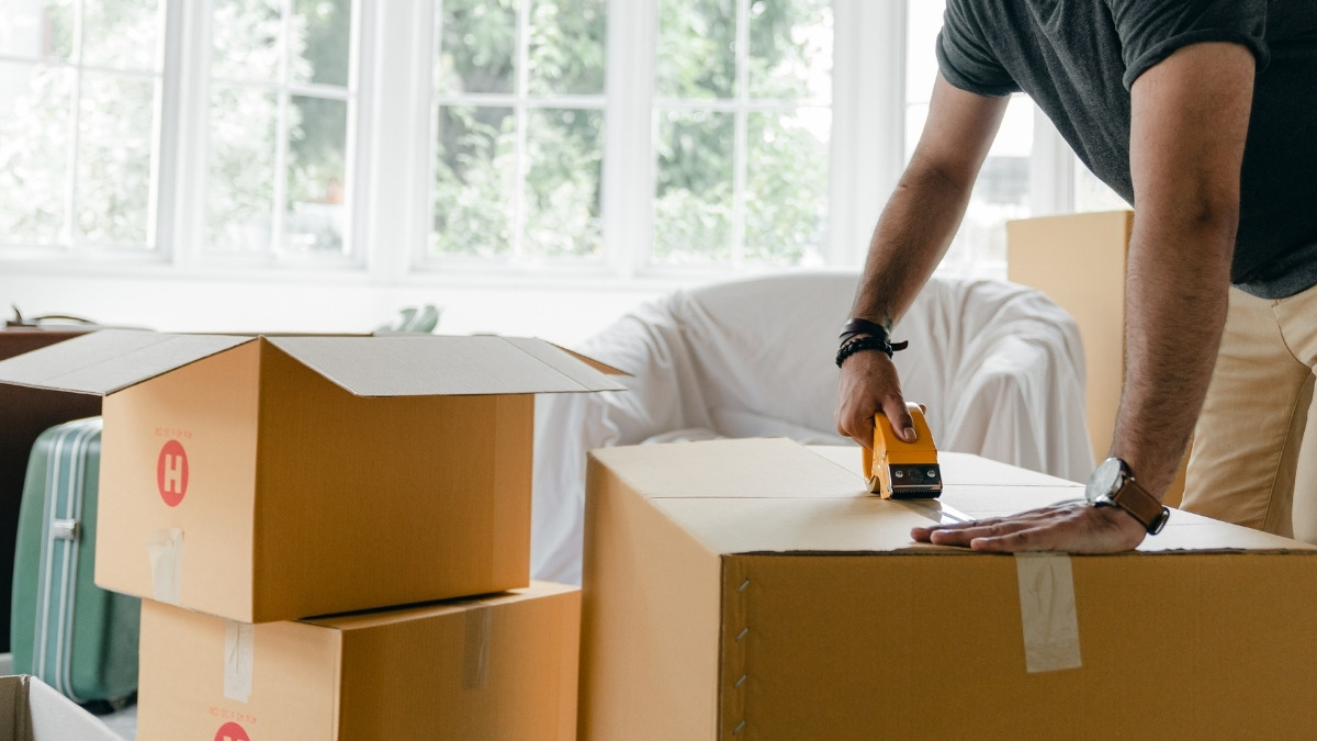 Man using a tape gun to seal cardboard