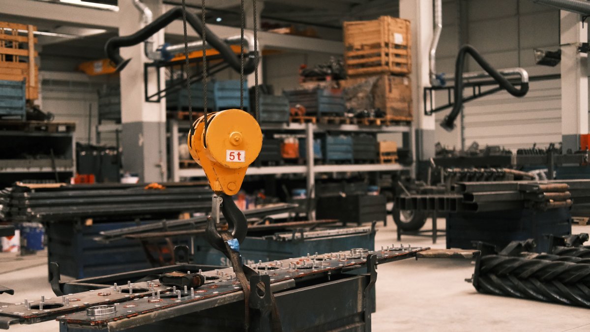 Close-up of a yellow industrial crane hook in a manufacturing workshop showcasing metalwork.