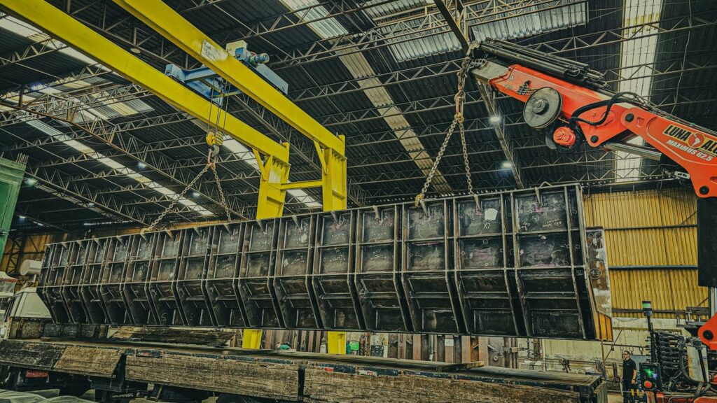 Robust industrial crane hoisting a large metal container inside a spacious warehouse