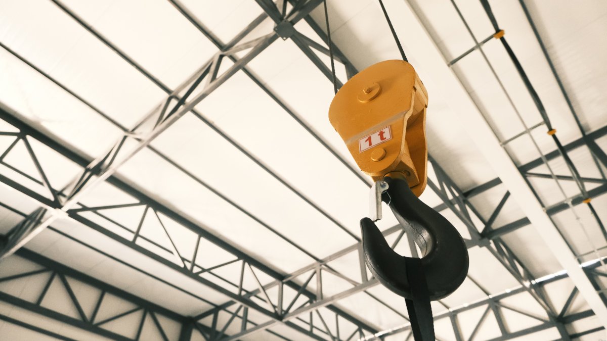 Close-up of a yellow crane hook inside a modern industrial facility
