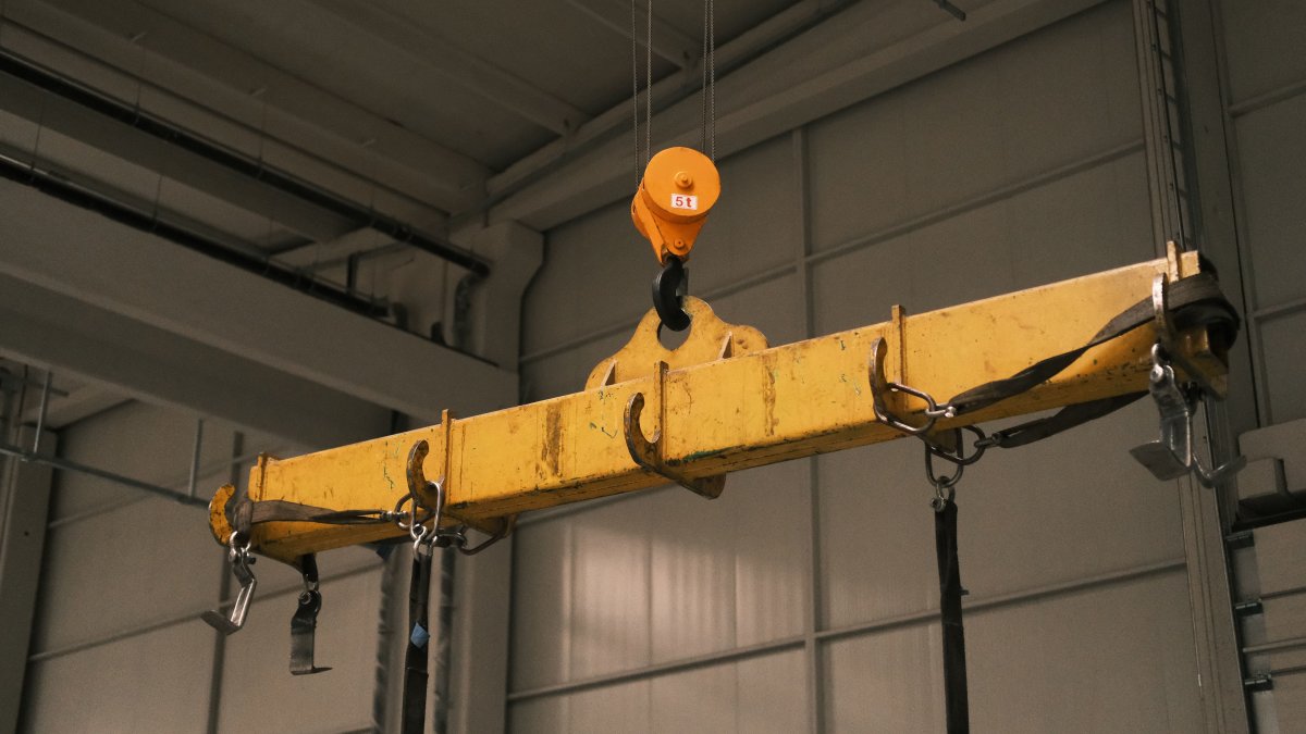 Close-up of a yellow industrial crane used in manufacturing, showing strength and machinery